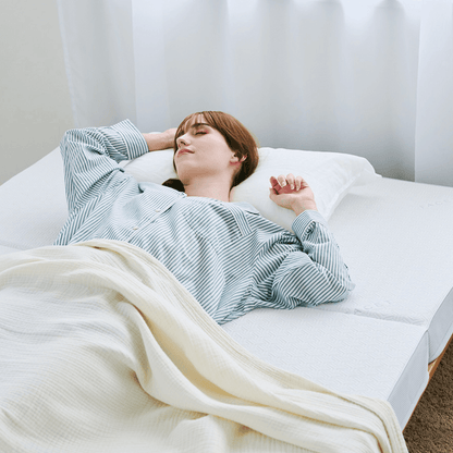カラーフォームのファセットの三つ折りマットレスの上で眠っている女性の写真